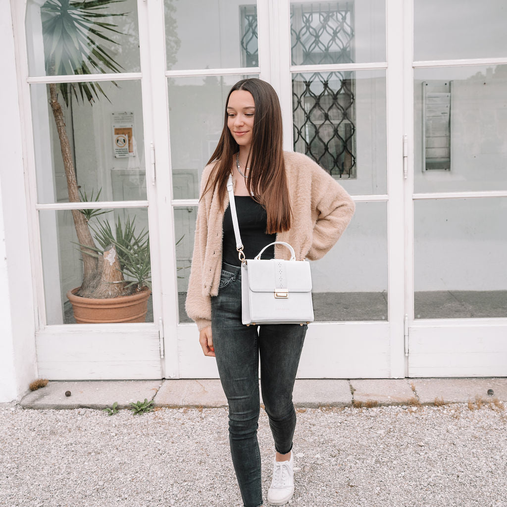A lady carrying a white top handle purse leather Ceci bag from a brand named Cocoona who produces quality bags made of Italien leather, sustainable productions, made to last